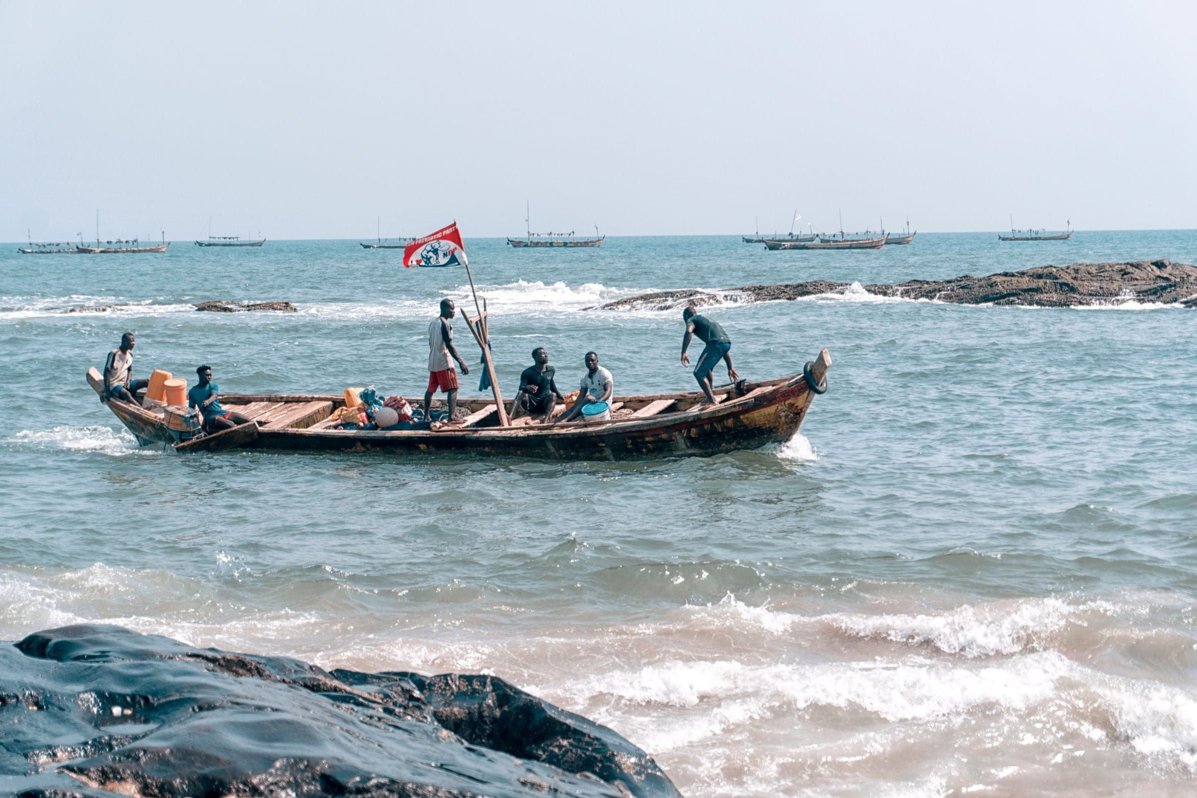 Fishermen launching a wooden boat off the coast at Elmina, Ghana