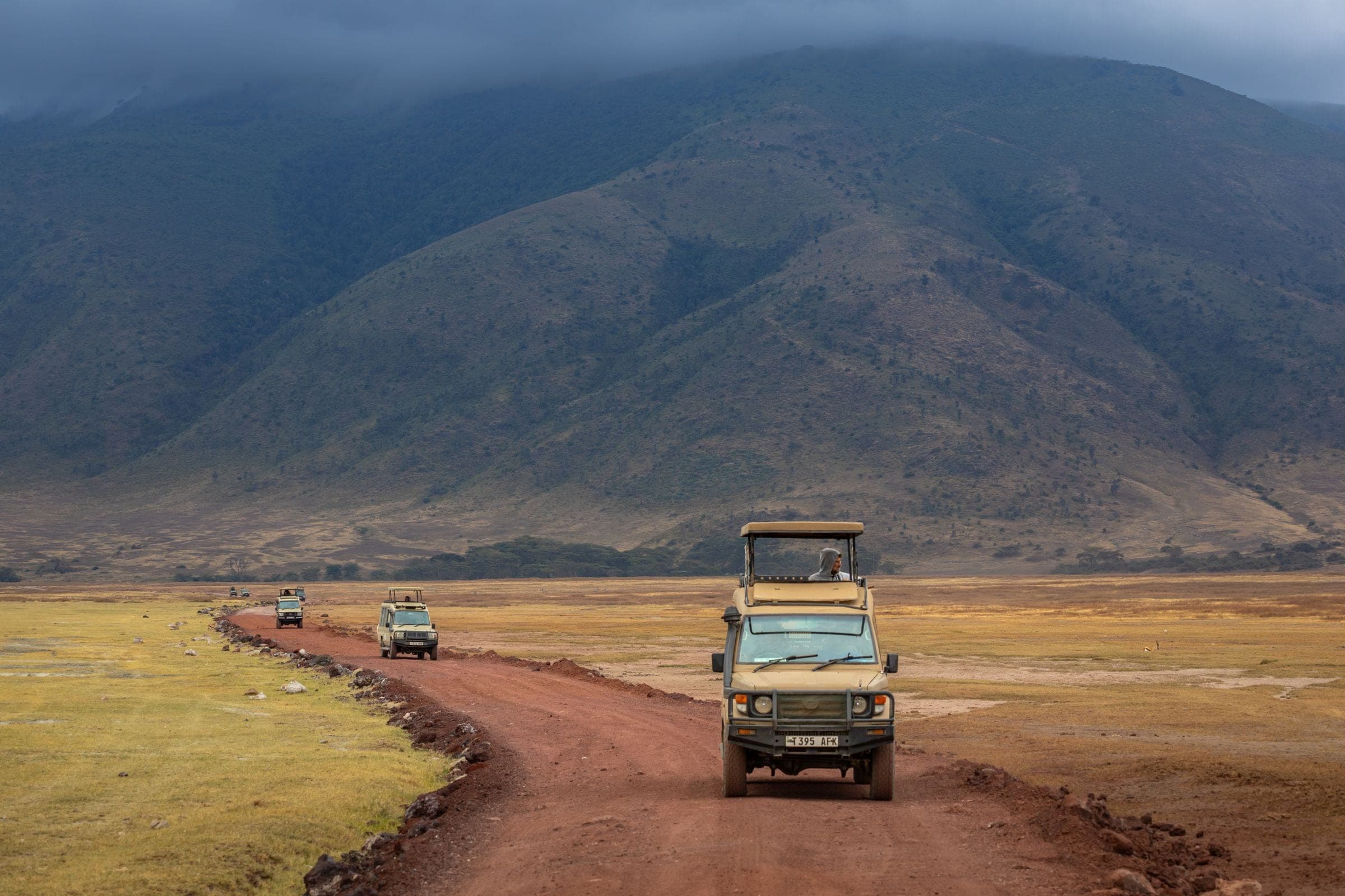 Safari vehicles on a red dirt road across the Ngorongoro Crater floor