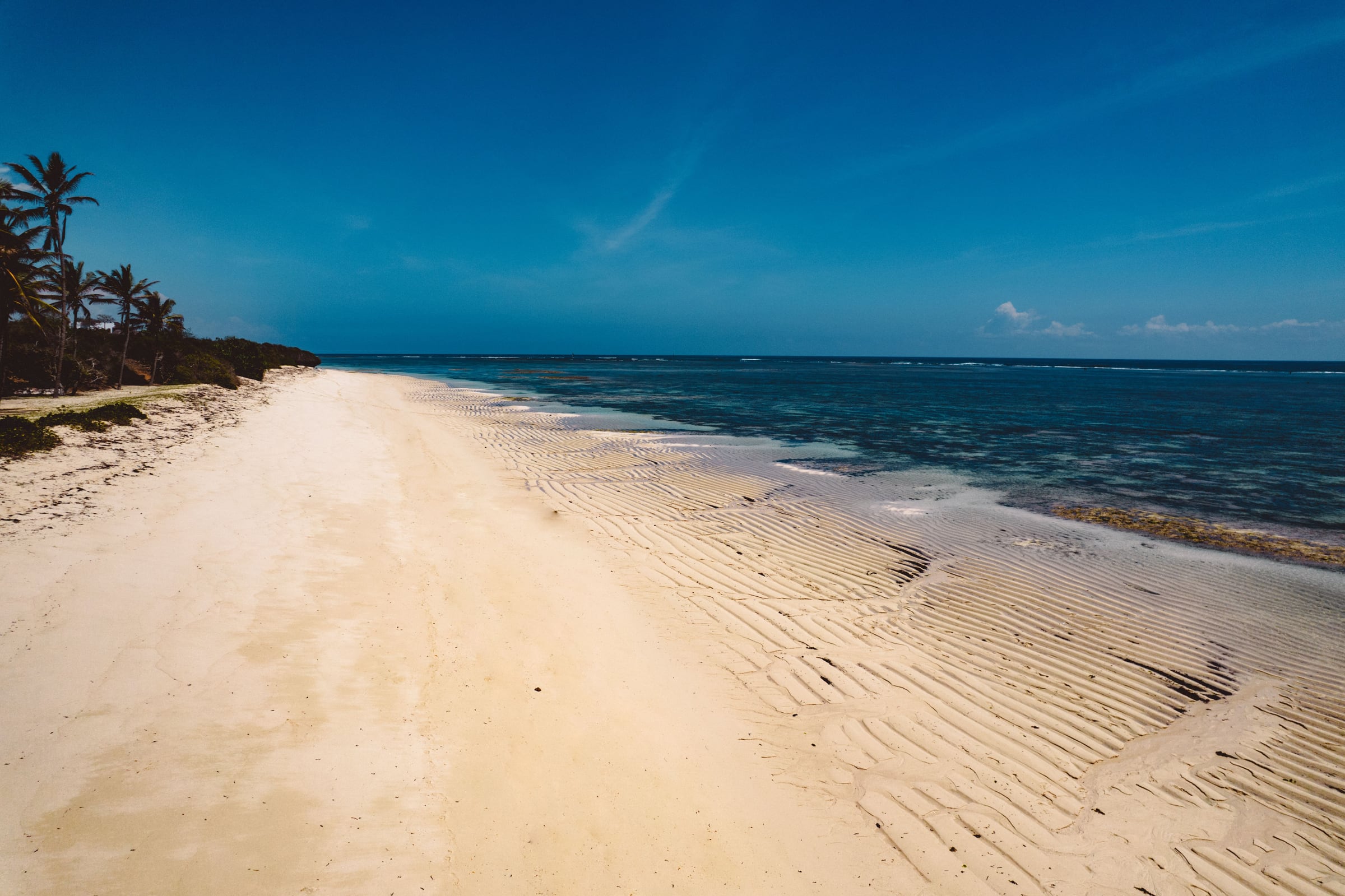 A wide white sand beach and clear blue water on the Kenyan coast