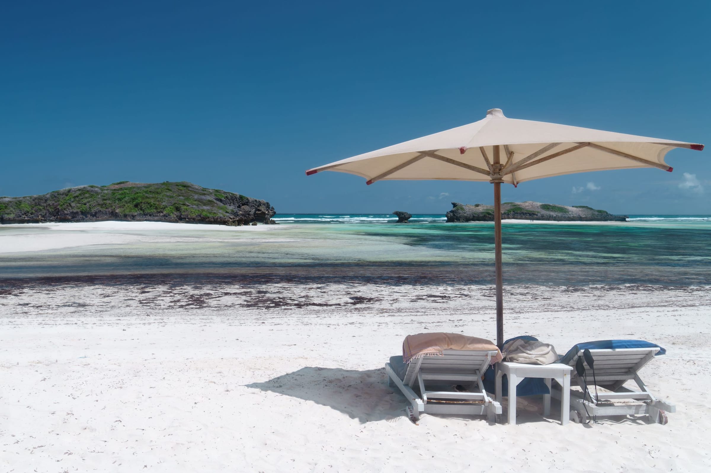 A beach umbrella and sun loungers on white sand on the Kenyan coast